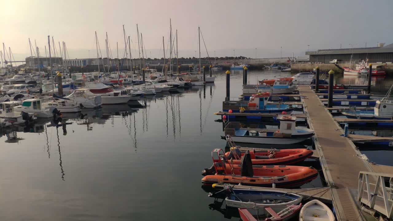 muchos barcos de pesca, veleros en el pequeño puerto con la ciudad detrás en un brillante amanecer soleado, tiro girando a la derecha