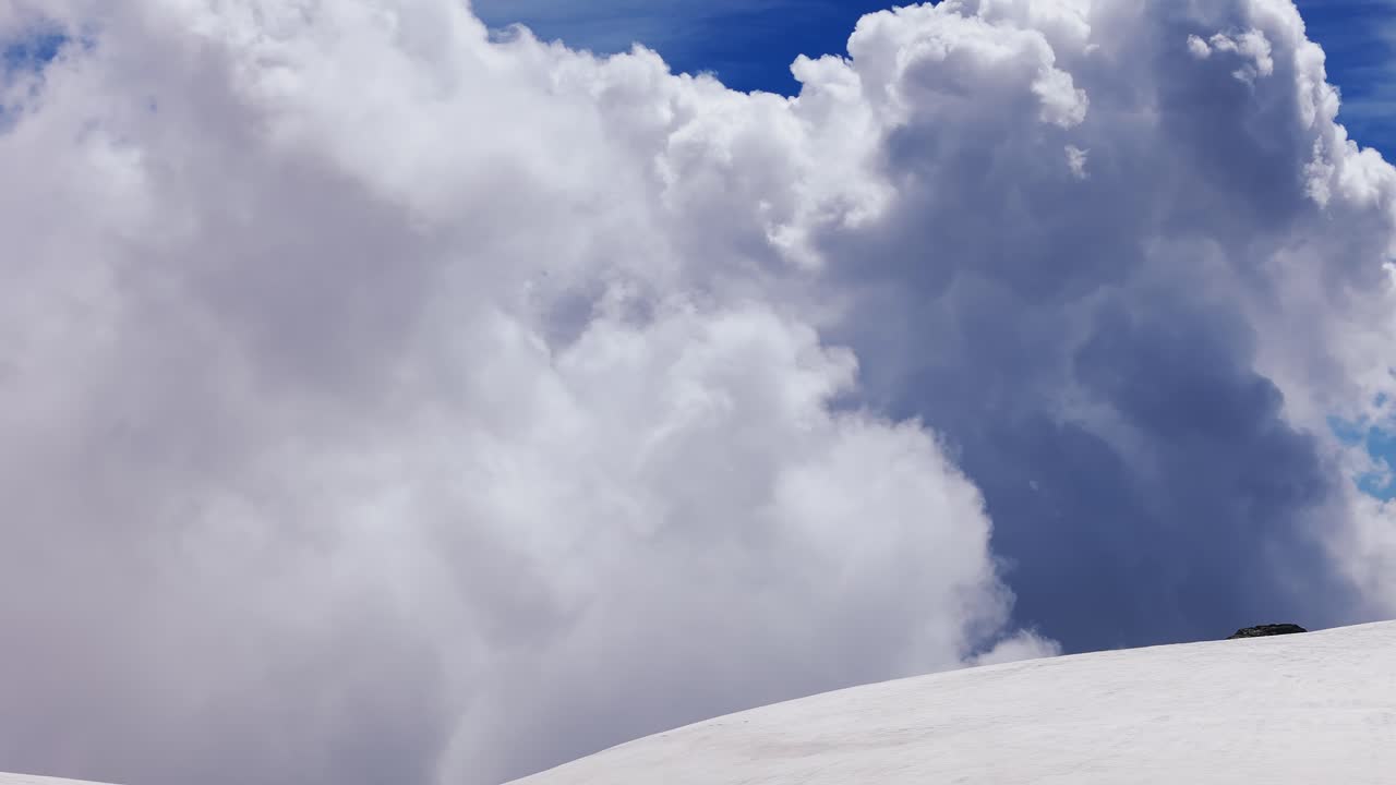 Dramatic Cumulus Clouds Over Snowy Mountain Peak