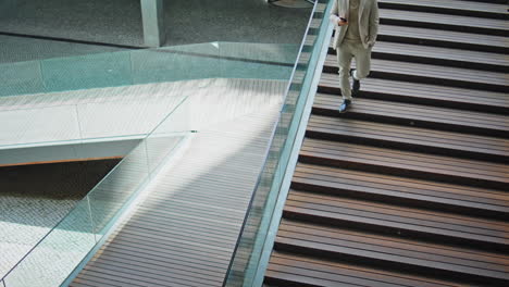 elegant man going downstairs holding smartphone. boss walking down staircase