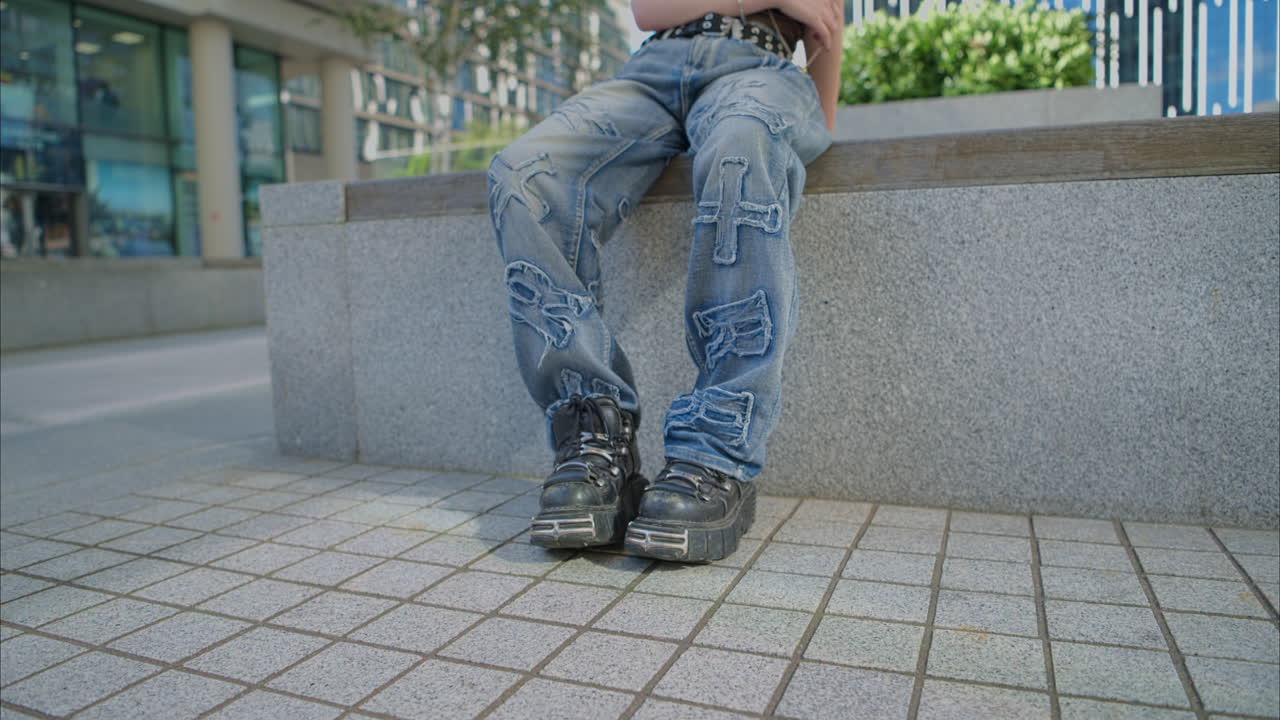 retrato de moda al aire libre de una mujer joven de estilo alternativo con tatuajes y perforaciones sentada fuera de edificios modernos filmada en tiempo real 1