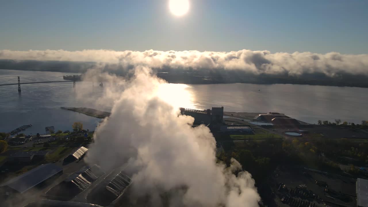 White smoke coming out of a factory by the river and polluting the air