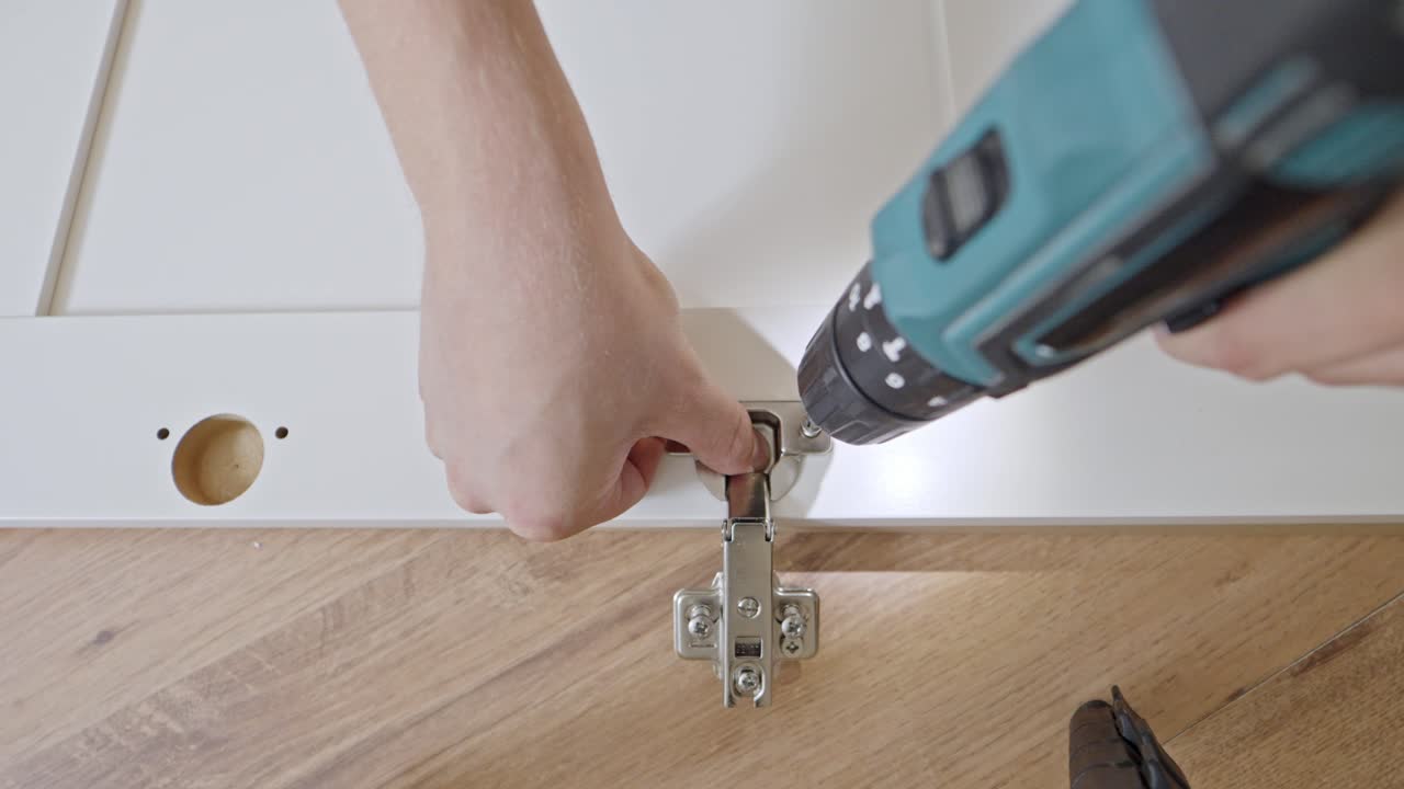 POV using electric drill to secure screw along self assemble closet door, top down
