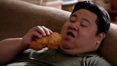 man eating fried chicken on a couch