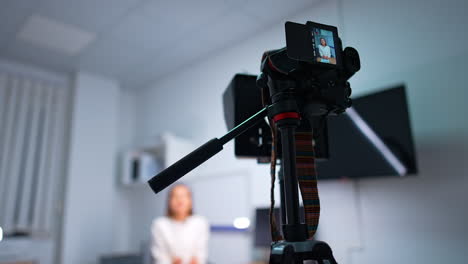 modern camera on tripod recording video blog. low angle view. woman influencer creates content for a vlog. blurred backdrop.