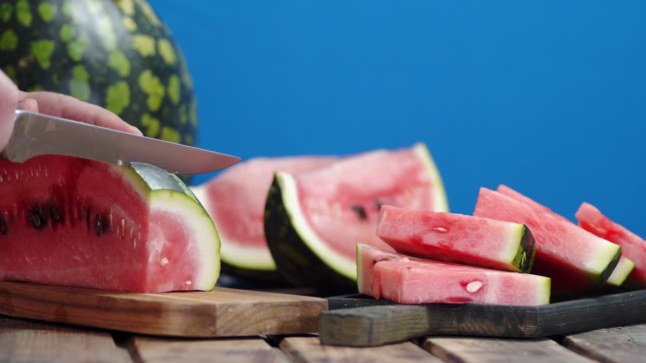 manos masculinas cortando sandía en pedazos en la tabla de cortar.