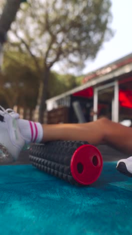 woman using foam roller for leg stretching outdoors