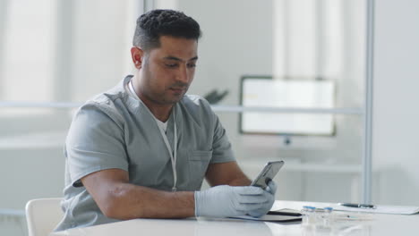 Médico-Masculino-De-Oriente-Medio-Que-Usa-Un-Teléfono-Inteligente-En-El-Trabajo