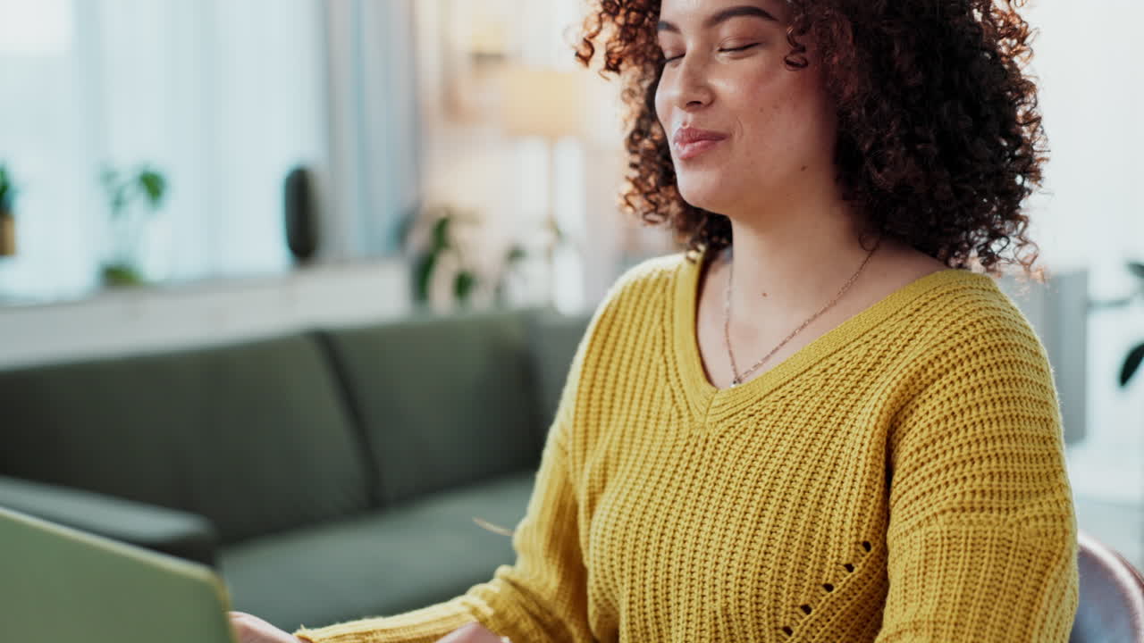 Woman with curly hair eating pizza and working on laptop