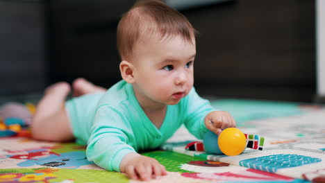 smart kid lies on belly and has a toy. lovely boy being active and yawning sweetly. close up.