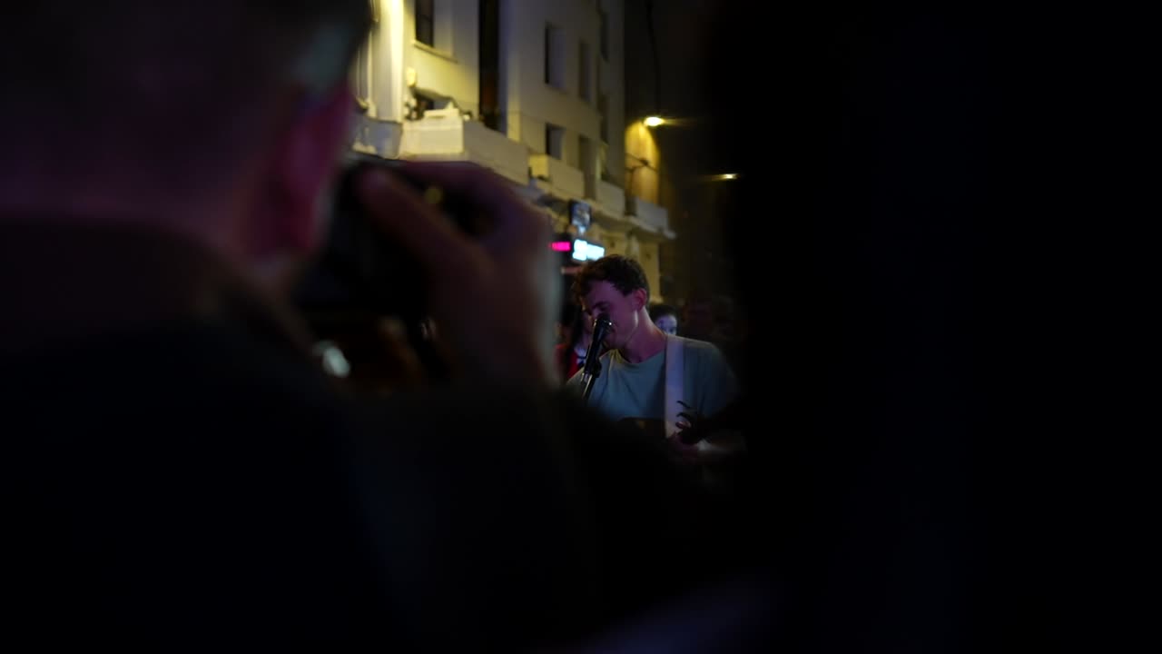 Street performer Myles Crossley captivates a crowd at night in Leicester Square, London