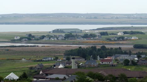 long distance shot of an airport, runway and airplane hangar in the distance beyond the small, seaside town of stornoway