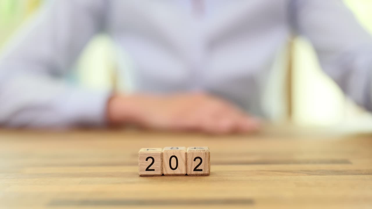 A hand arranging wooden blocks to form the year 2024, symbolizing the new year and future