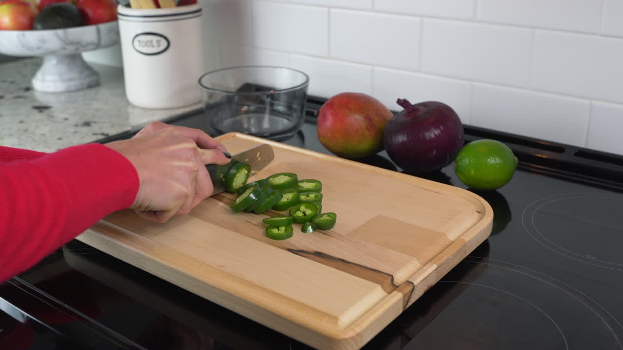 mujer cortando jalapeños picantes en una cocina limpia y colorida