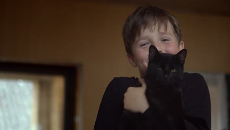 portrait of a laughing boy with a black cat in his arms