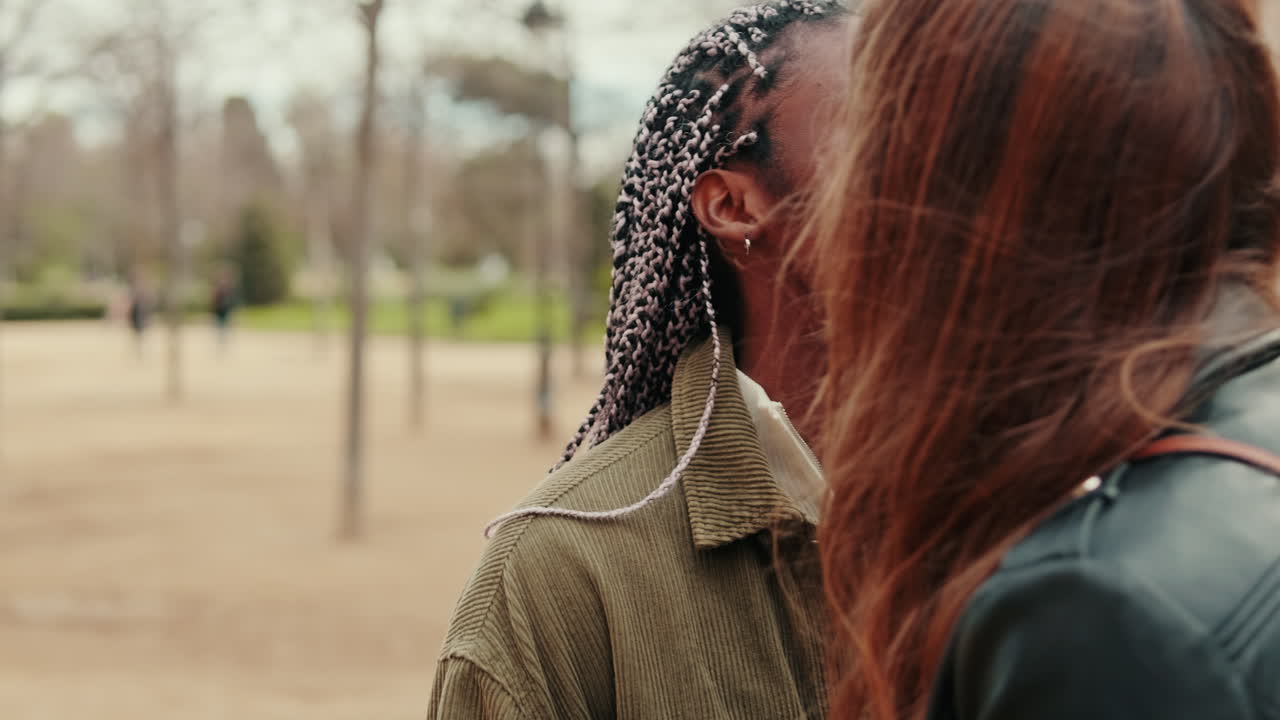 Giovane donna nera felice con le trecce che parla in un parco