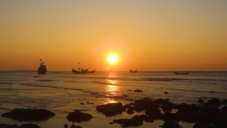 pirate ships float on caribbean sea at calm orange sunset, long shot