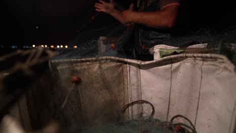 vista de ángulo bajo desde una canasta mientras un pescador saca una red de pesca para ponerla en la noche