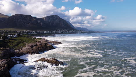 frothing whitewash on rocky coastline as angry waves crash into it, hermanus