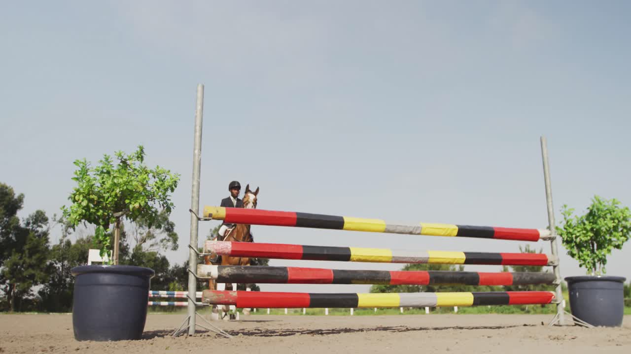 아프리카계 미국인 남자가 드레저 말과 함께 장애물을 뛰어넘고 있습니다.