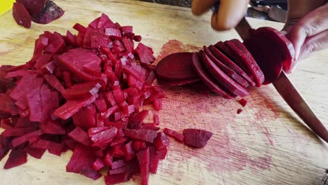 close up of female hands in gloves cutting beet on kitchen board