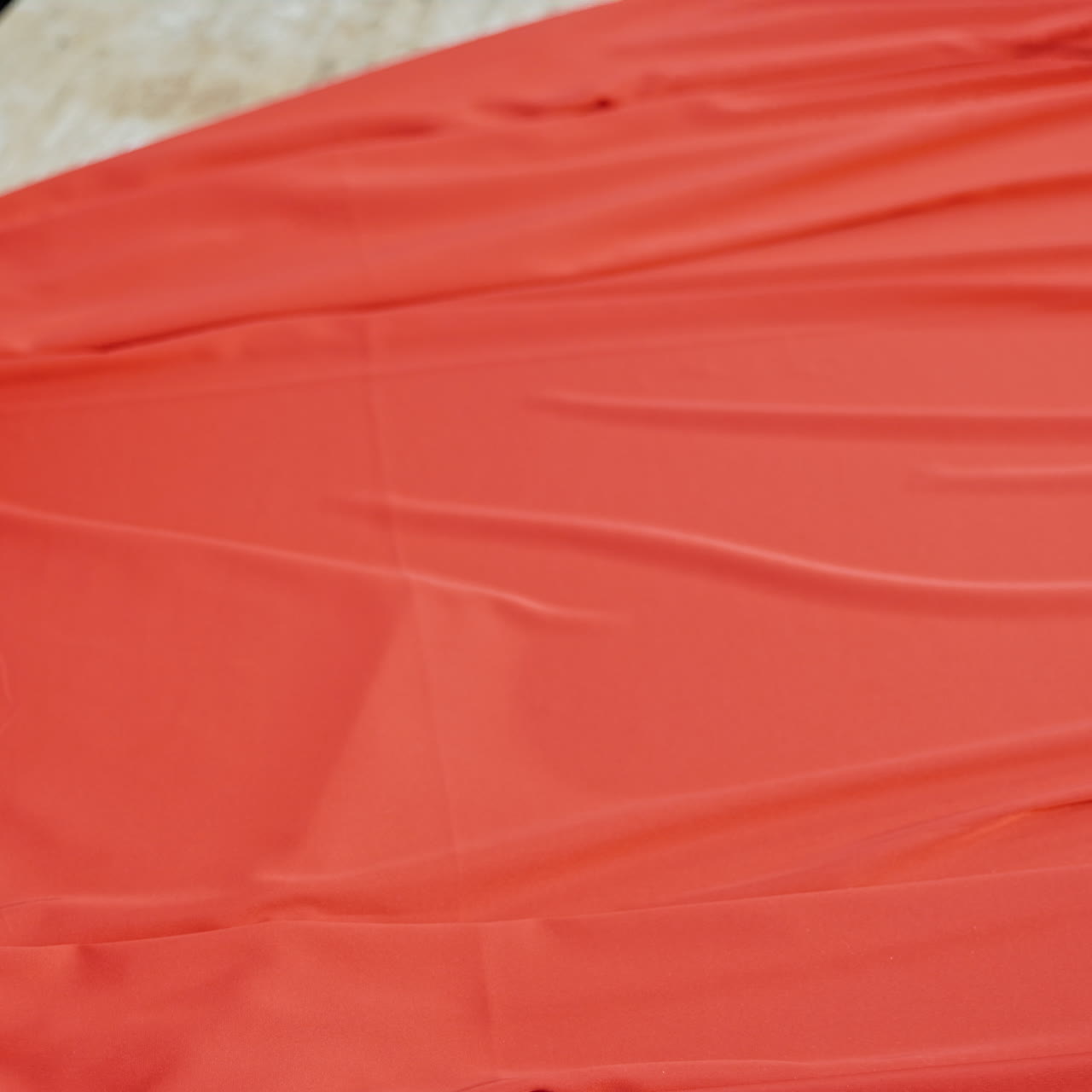 Professional tailor layng bright red fabric on a table. Work place table of sewer and a big piece of red cloth in workshop.
