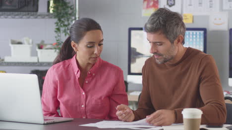 Businessman-And-Businesswoman-Disagreeing-In-Creative-Office-Working-At-Desk-On-Laptop