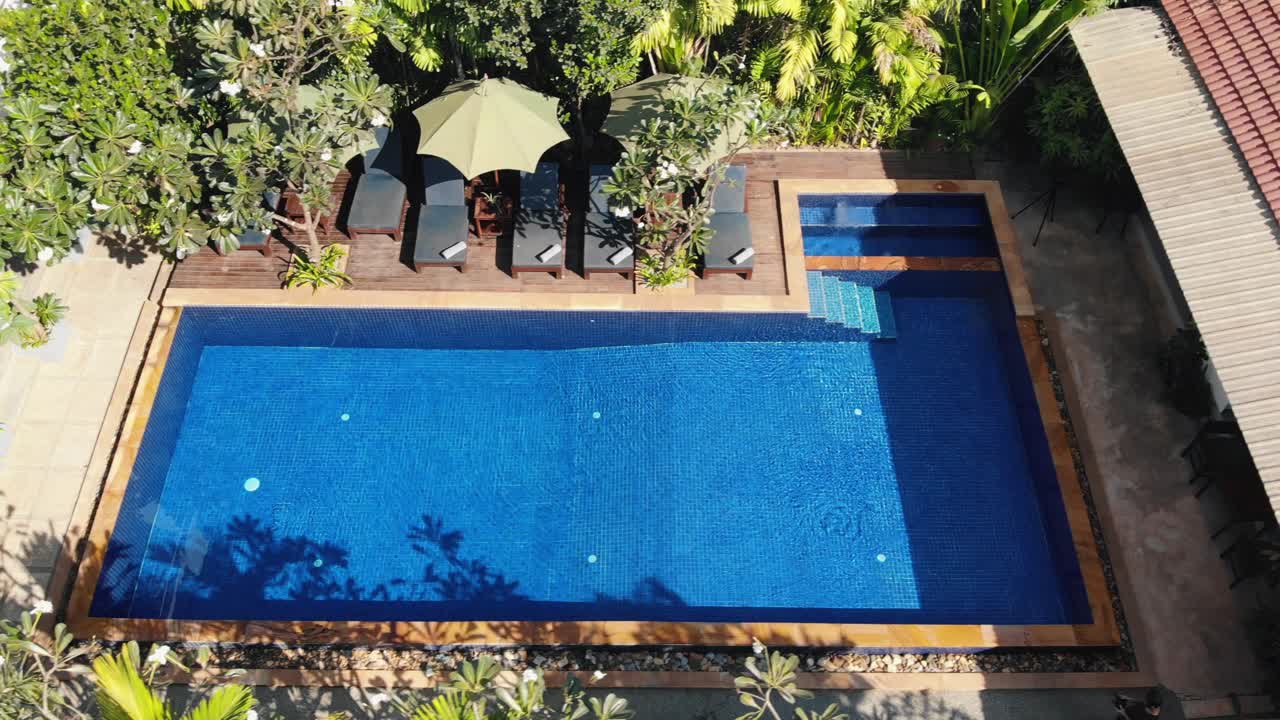 Høj sporingsdroneoptagelse af et tropisk hotelområde og swimmingpool