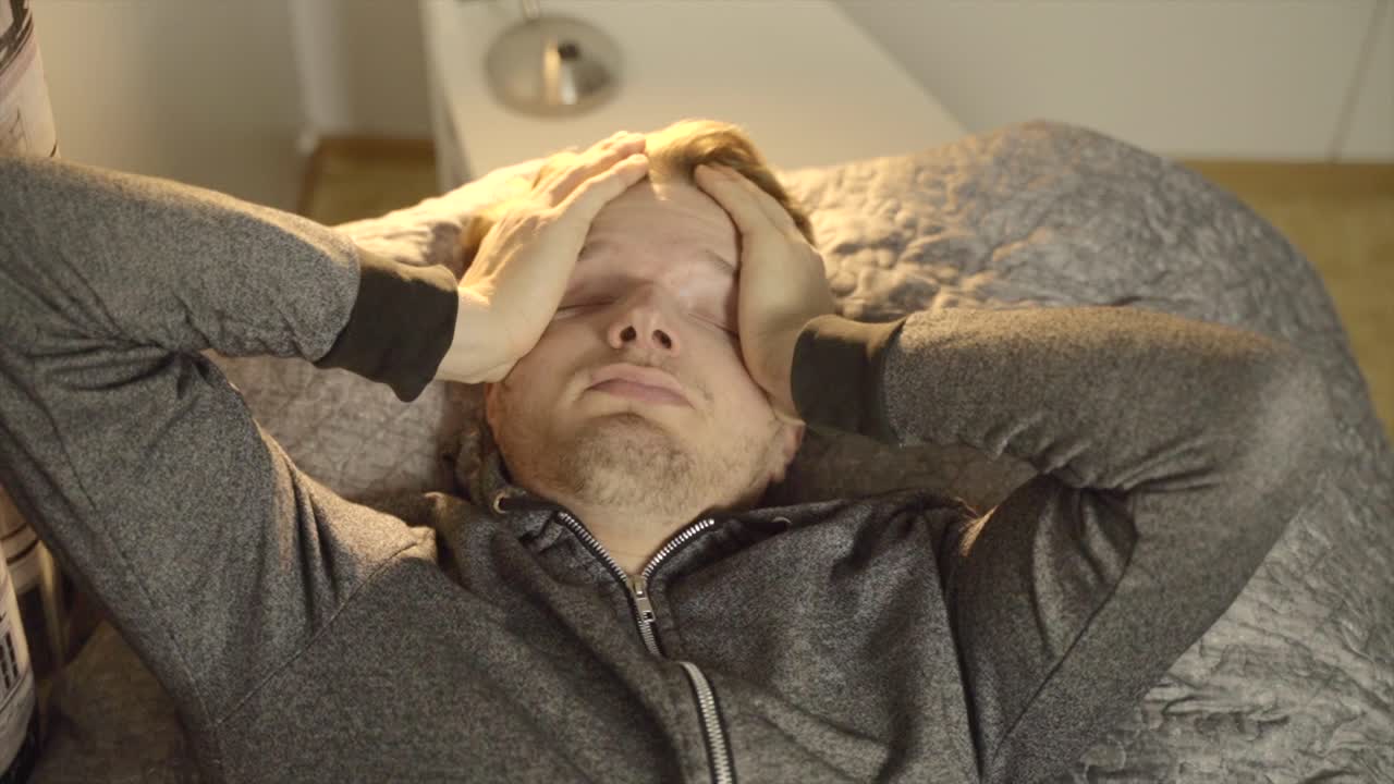 한 젊은 백인 남자가 지치고 피곤하여 침대에 누워 있다