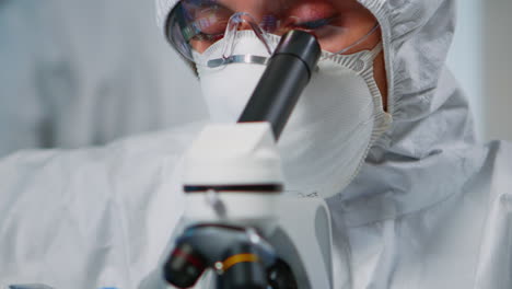 close up of experienced biologist in ppe suit working on microscopes