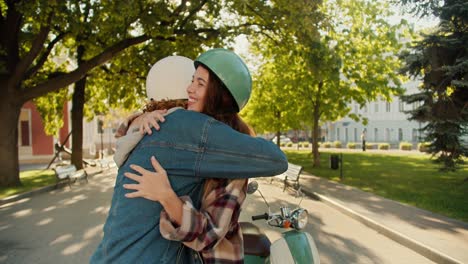 Ein-Glückliches-Paar:-Ein-Brünettes-Mädchen-In-Einem-Karierten-Hemd-Und-Einem-Grünen-Motorradhelm-Und-Ihr-Freund-In-Einem-Jeanshemd-Umarmen-Sich-Und-Schauen-Sich-In-Der-Nähe-Eines-Mopeds-In-Einem-Sommerlichen-Stadtpark-An