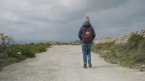 young woman walking on a rural road during a day trip in the mediterranean nature on a cloudy winter day