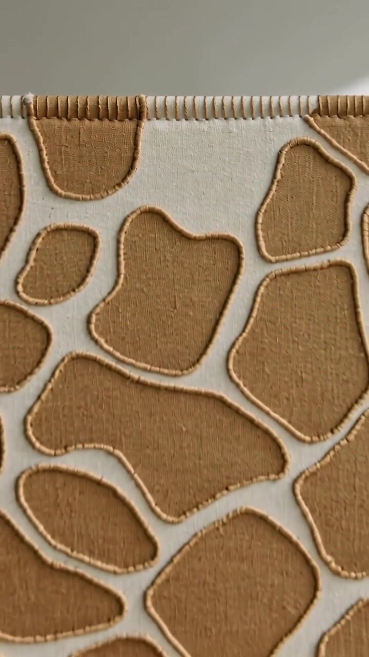 Vertical video: Pulling back camera revealing cloth panel on wall, showing tan patches and hem
