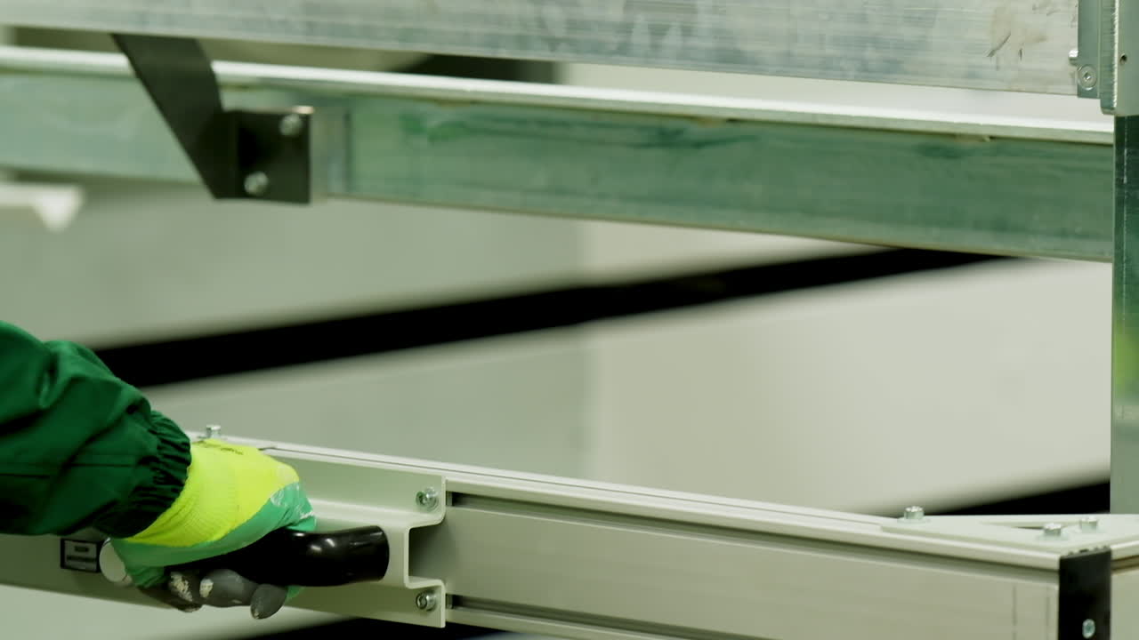 Manufacture of doors. Hands of industrial worker inside factory. Metal frame for door production. Close-up.