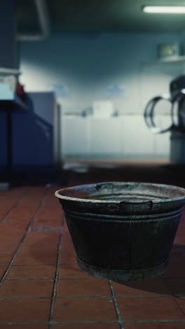 old rusty metal bucket on a tile floor in a dark room