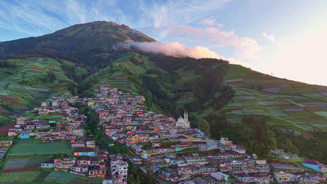 Veduta aerea di un villaggio colorato su un pendio montano all'alba, Indonesia. Paesaggio rurale, turismo naturalistico e riprese aeree panoramiche dell'altopiano