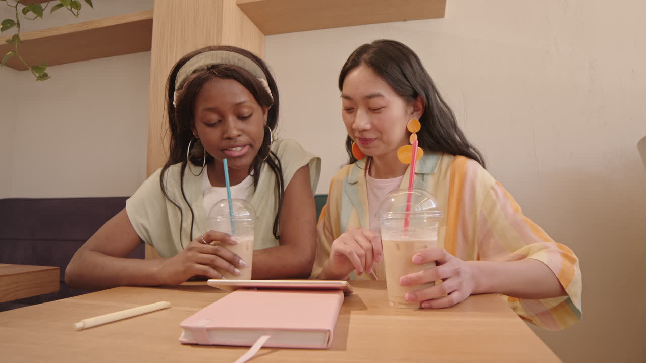 Girlfriends Using Digital Tablet at Cafe Table