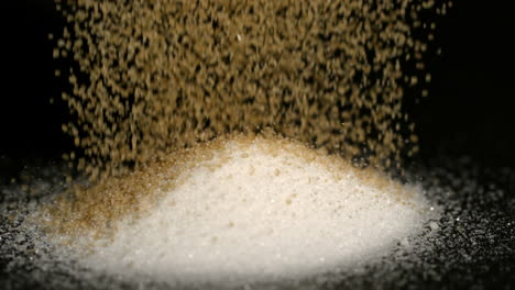 Golden-sugar-pouring-on-white-sugar-on-black-background