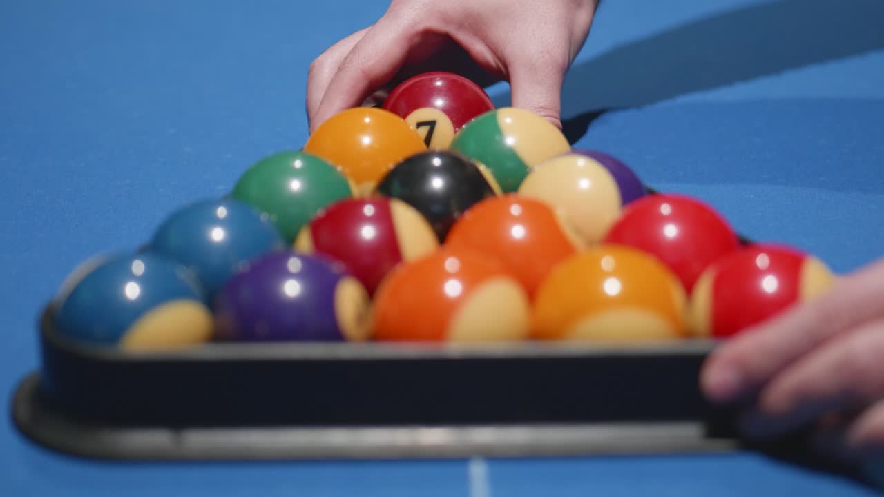 depois de colocar as bolas, as mãos removem o triângulo preto do snooker para iniciar o jogo.