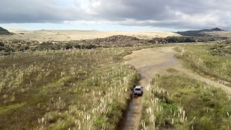 camioneta de 4 ruedas conduciendo a lo largo del arroyo te paki por grandes dunas de arena cerca de cabo reinga en nueva zelanda