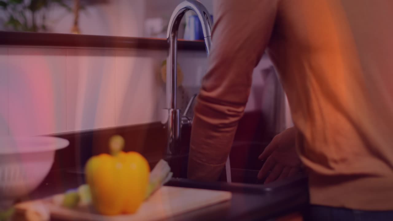 Un cuisinier amateur ouvre un robinet de cuisine chromé et rince des asperges sous l’eau courante pour la cuisson