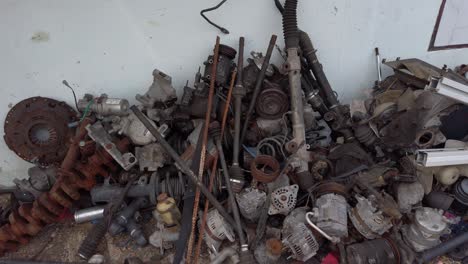toma panorámica de un montón de piezas de máquinas de metal chatarra desordenadas contra una pared blanca