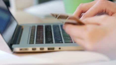 manos femeninas escribiendo el número de tarjeta de crédito en el teclado de la computadora portátil
