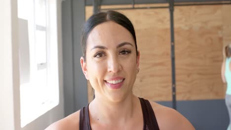 Retrato-De-Una-Mujer-Birracial-Sonriente-E-Inalterada-Tomando-Un-Descanso-Del-Entrenamiento-Cruzado-En-El-Gimnasio,-Cámara-Lenta