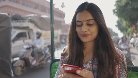 a young woman is sitting in an auto-rickshaw with face mask using mobile phone