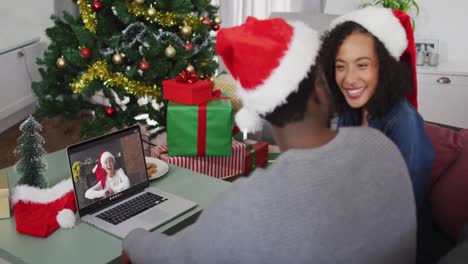 Glückliches-Afroamerikanisches-Paar-Bei-Einem-Videoanruf-Auf-Dem-Laptop-Mit-Einer-Freundin-Zur-Weihnachtszeit