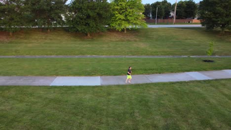 drone footage of man running through park slowly backing away to reveal larger view