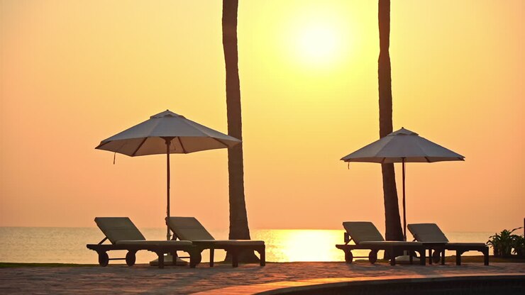 Ombrelloni e sdraio vuoti su una spiaggia sabbiosa della Thailandia con il mare sullo sfondo al tramonto