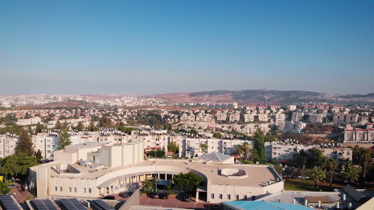 Aerial View of a Residential Cityscape with Numerous Buildings and Distant Hills Under a Clear Sky