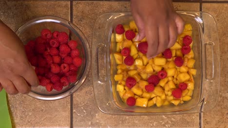 Making a peach raspberry crisp - overhead view of hands at work