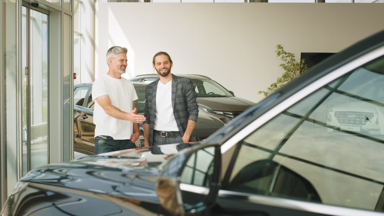dos hombres discutiendo un coche en una sala de exposiciones